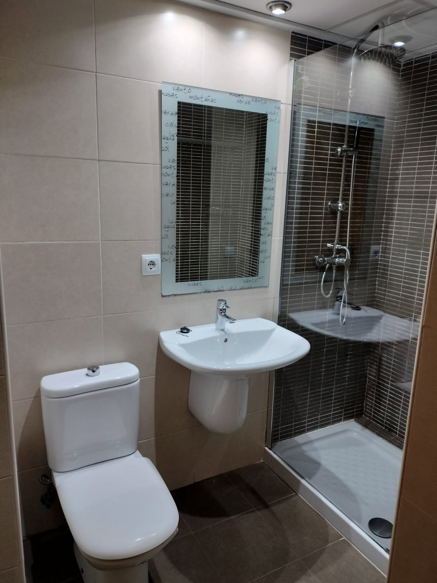 Cuarto de baño limpio con lavabo, inodoro, espejo y plato de ducha